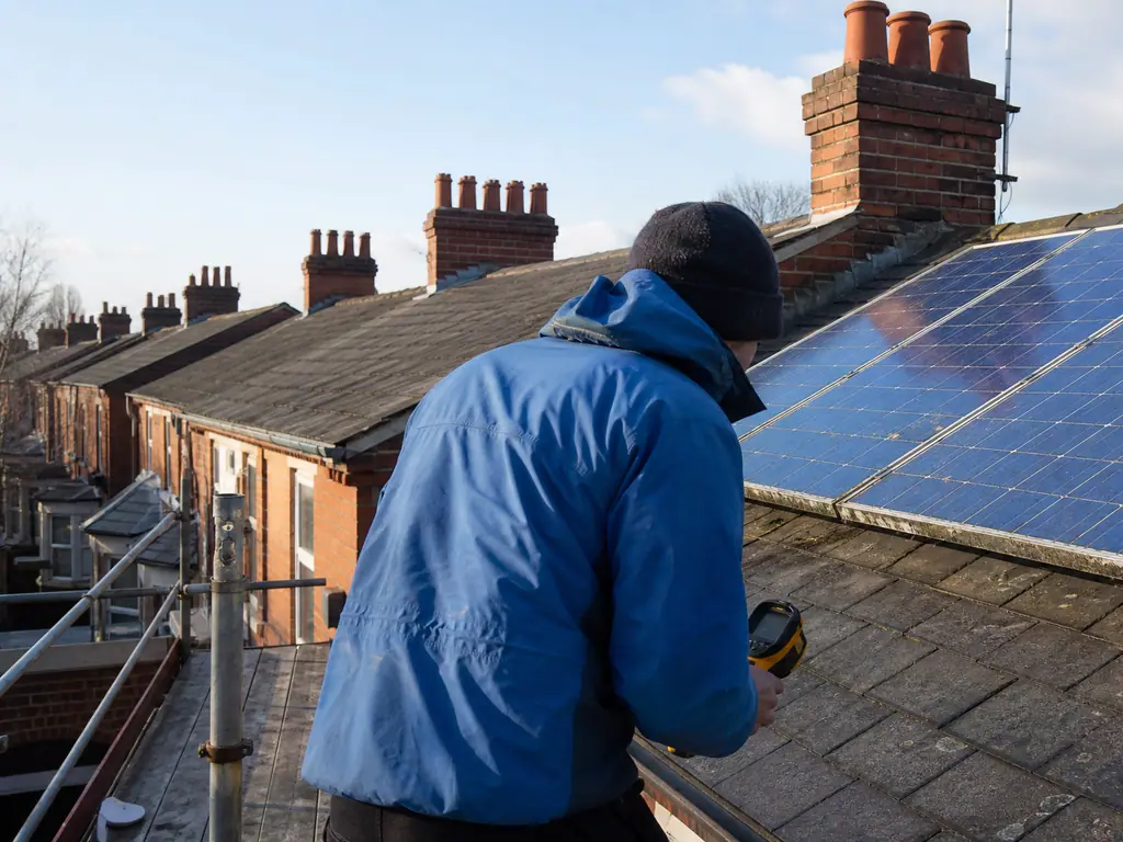 Engineer inspecting older solar panels from a scaffold on a Derby Victorian terrace