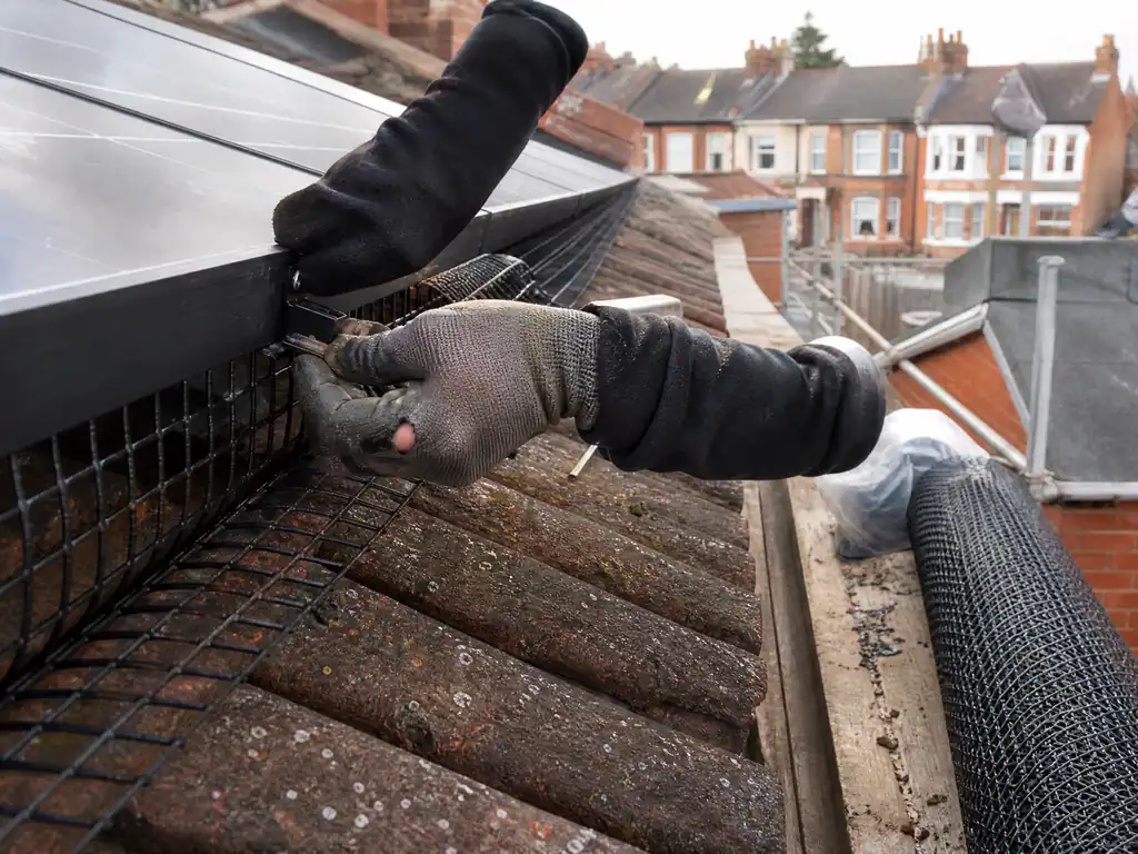 Installer clipping bird mesh to the edge of a solar array on a Derby semi