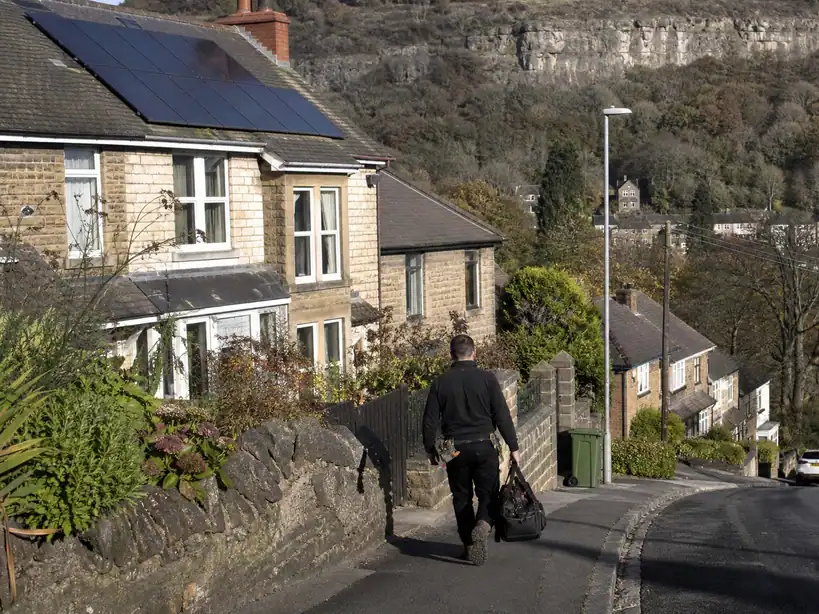 Solar panels on a stone house on a hillside street in Matlock